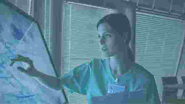 Kvinna inom vården arbetar vid en dataskärm